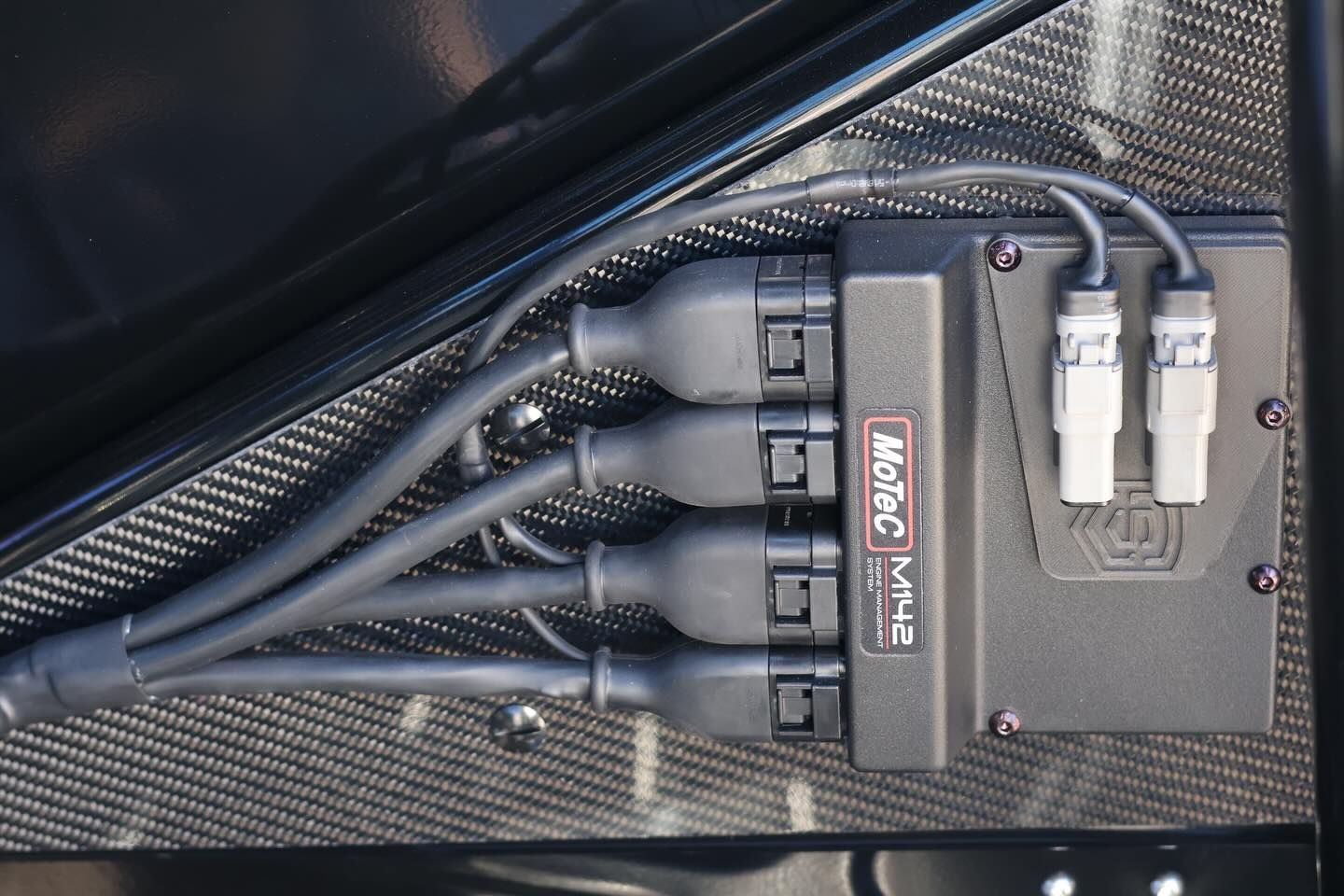 Close-up of a black cable organizer with several plugged-in connectors and braided cables inside a case