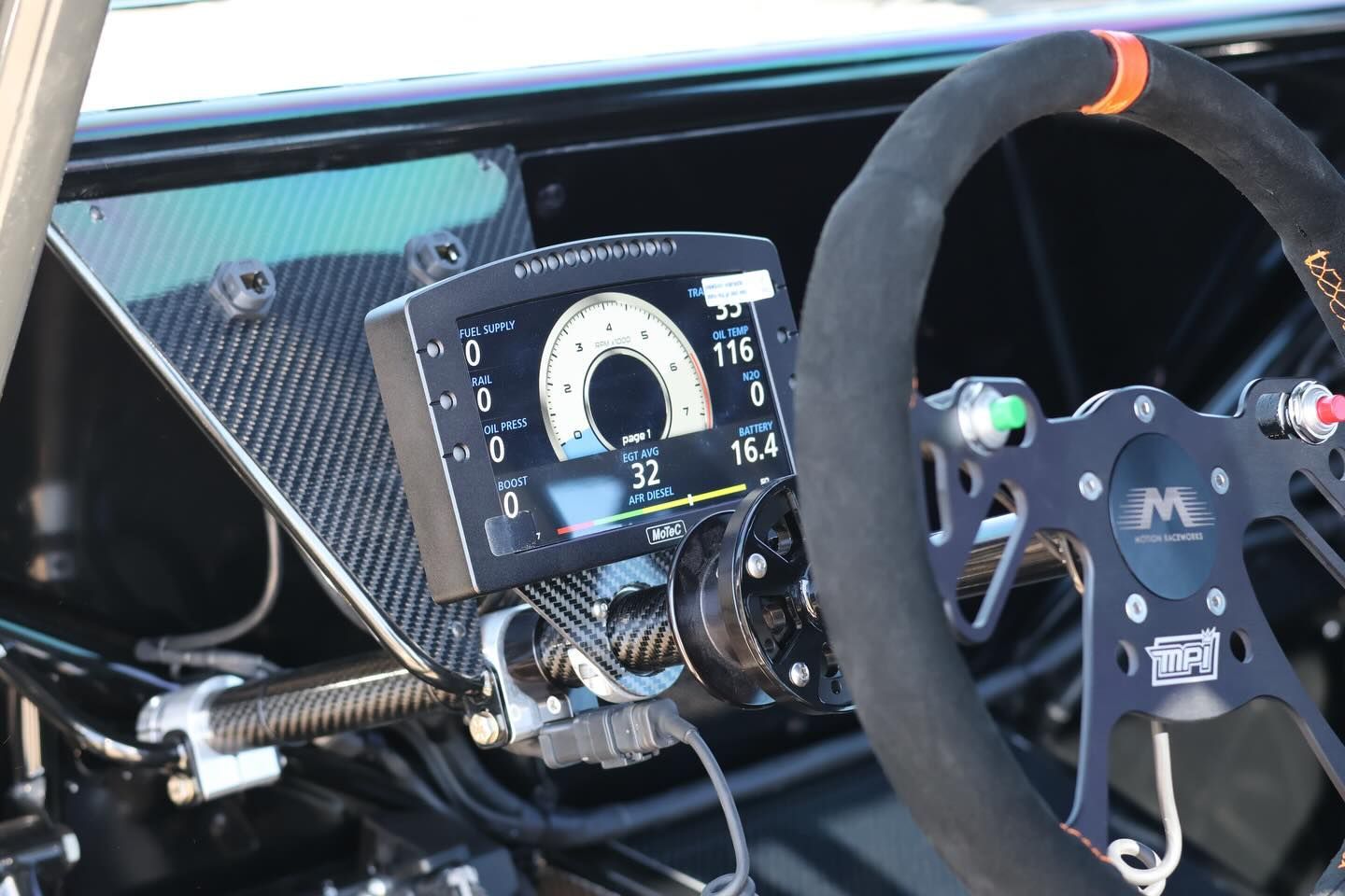 Race car cockpit with digital dashboard, steering wheel, and carbon-fiber interior details