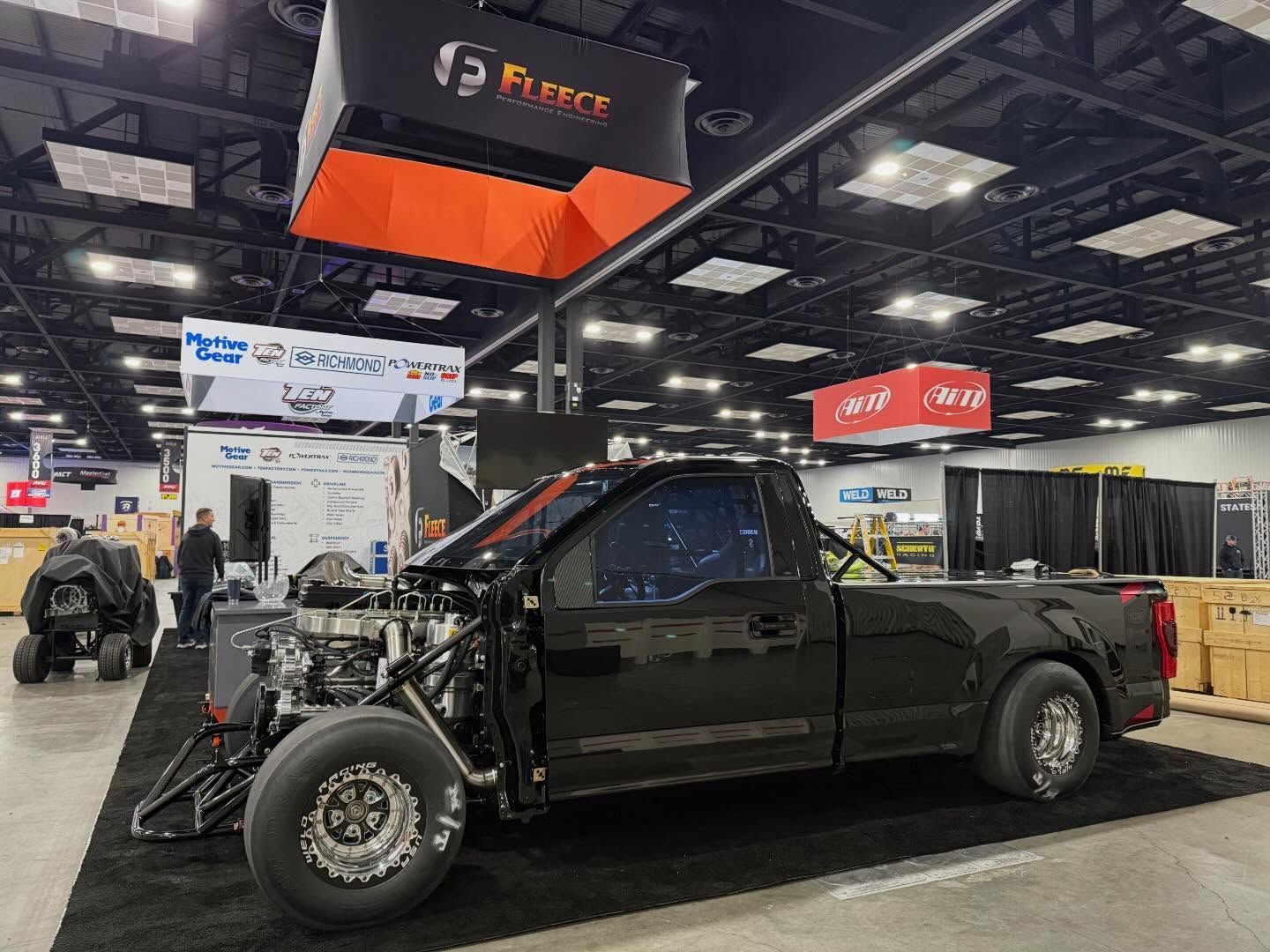 Lifted black pickup truck on display at an indoor auto show booth