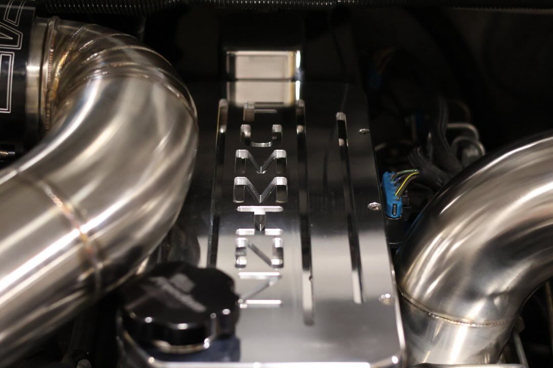 Close-up of a polished engine cover with chrome intake pipes on both sides.