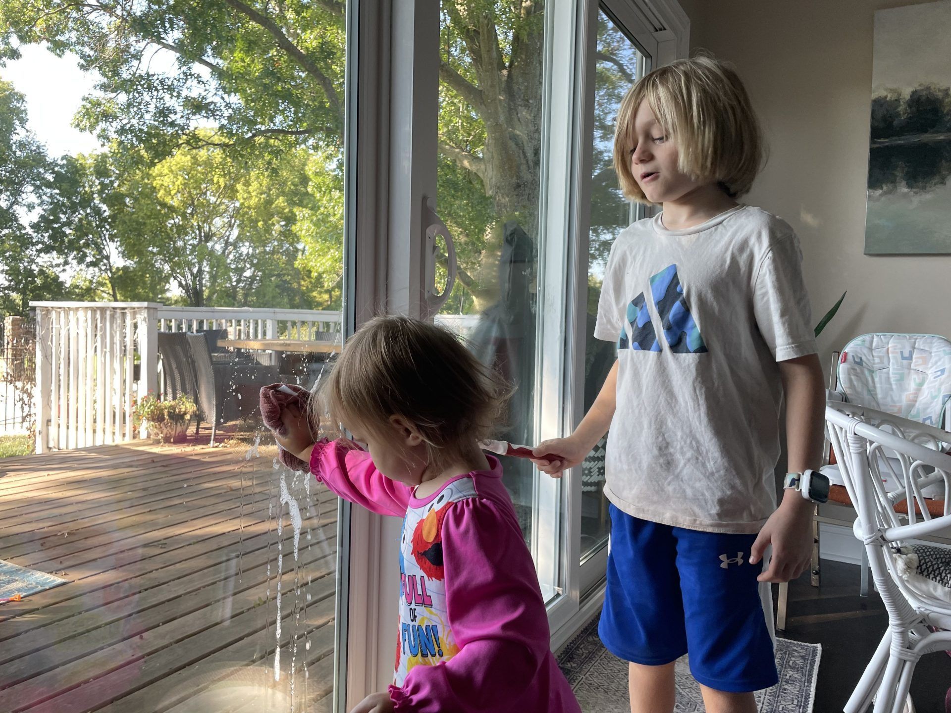 Toddler and Grade School Children Helping Clean Windows At Home