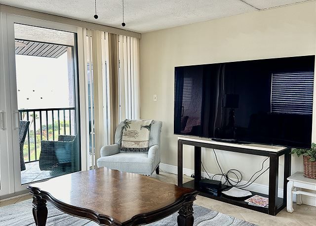 A living room with a large flat screen tv and a coffee table.