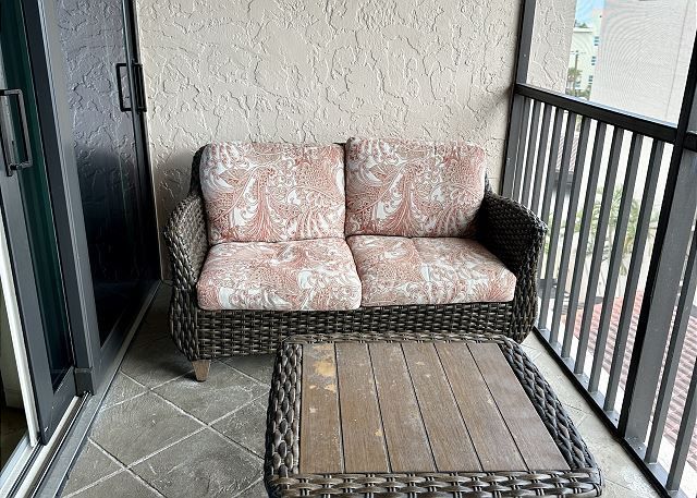 There is a couch and a table on the balcony.