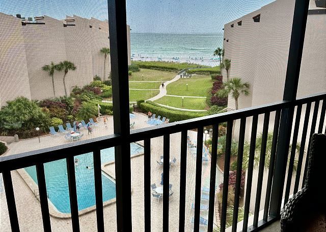 A balcony with a view of a pool and the ocean