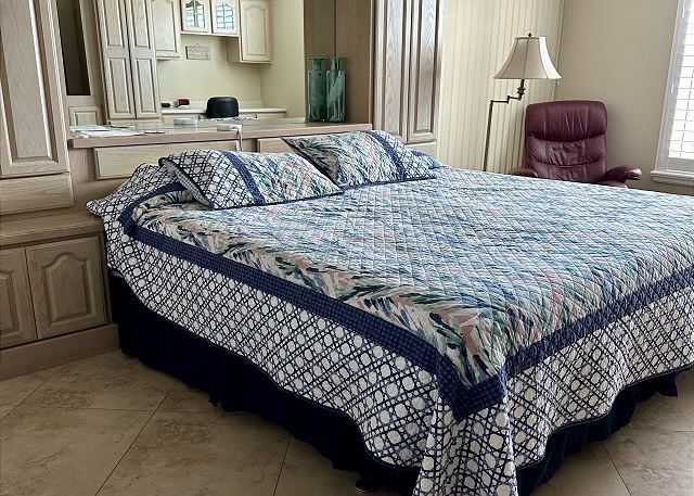 A bedroom with a king size bed and a chair.