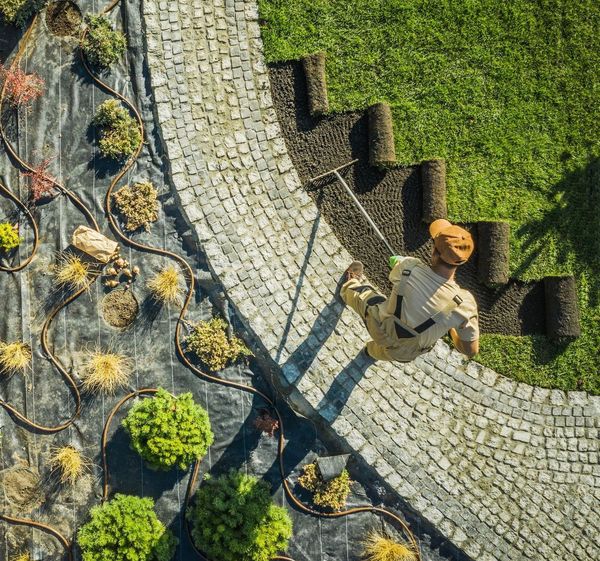 An aerial view of a man cutting grass with a lawn mower.