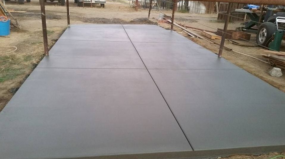 A large concrete floor is being built in a yard.