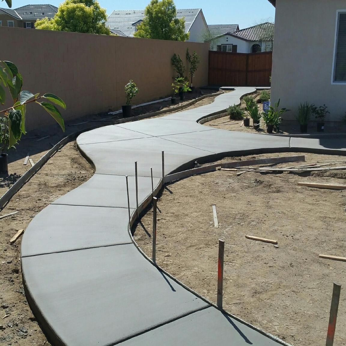 A curved concrete walkway is being built in a backyard