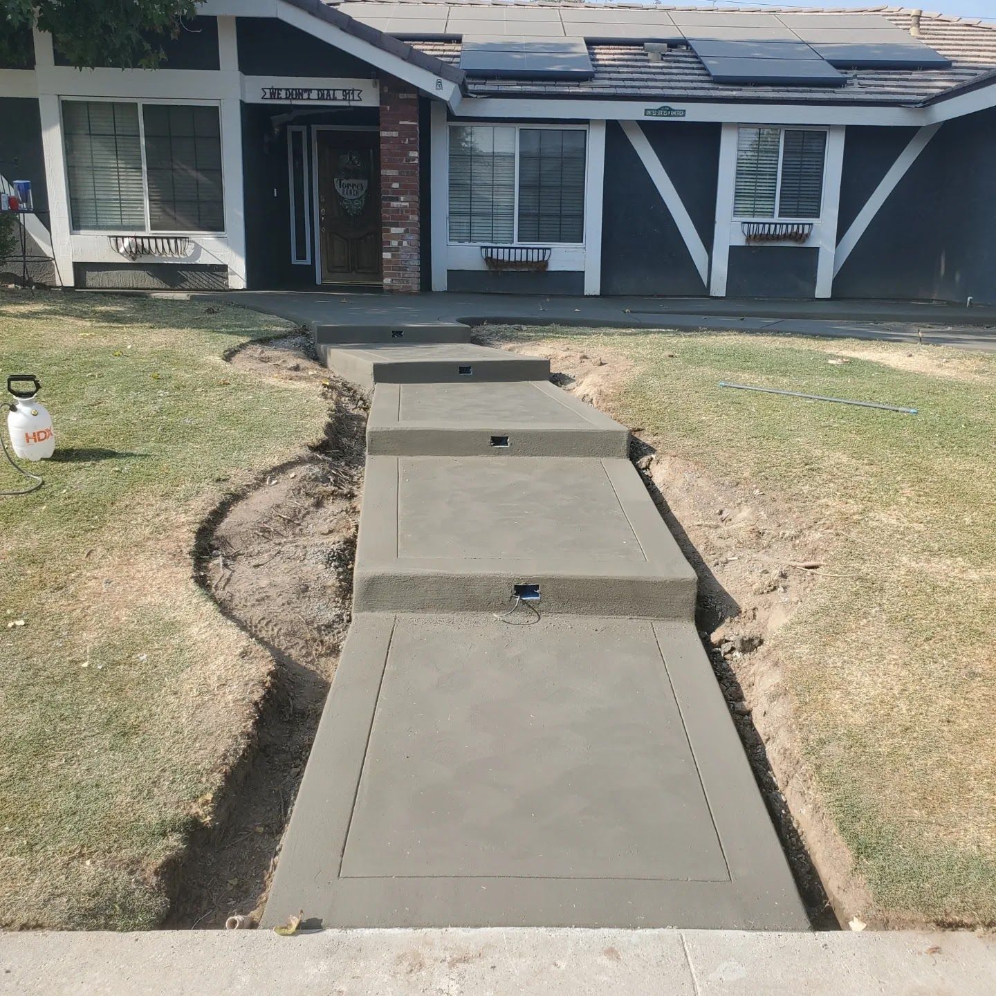 A concrete walkway is being built in front of a house