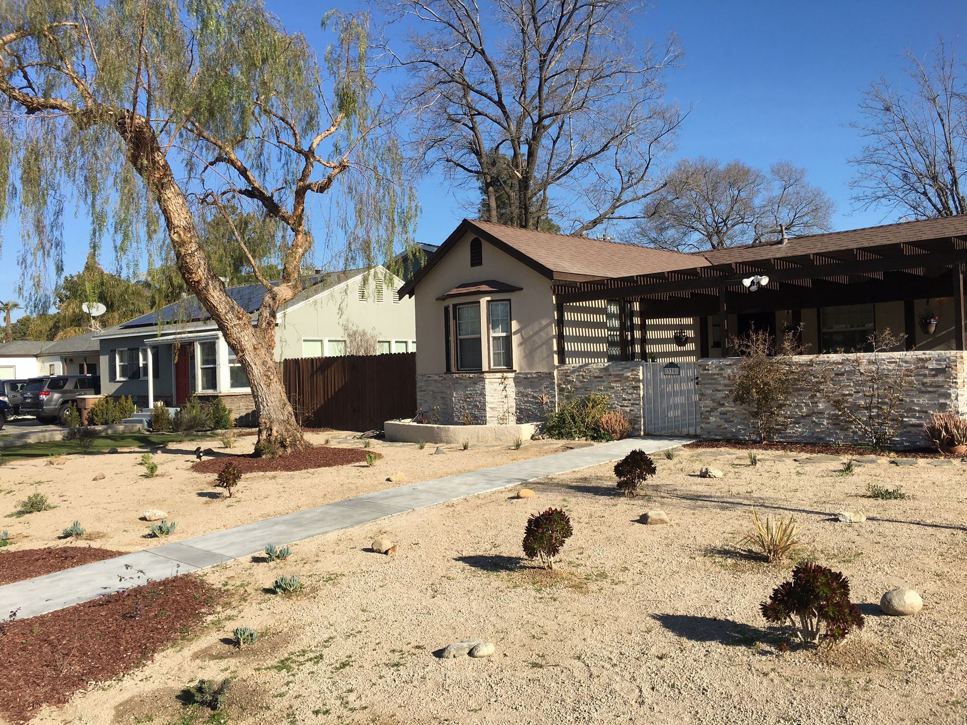 A house with a stone wall and a walkway in front of it