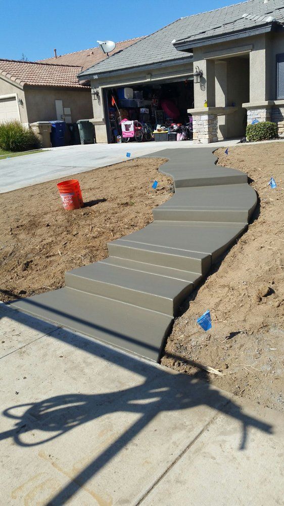 A concrete walkway is being built in front of a house.