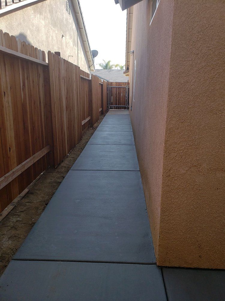 A sidewalk leading to a house with a wooden fence