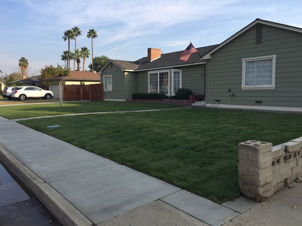 A house with a lush green lawn and a flag on the roof
