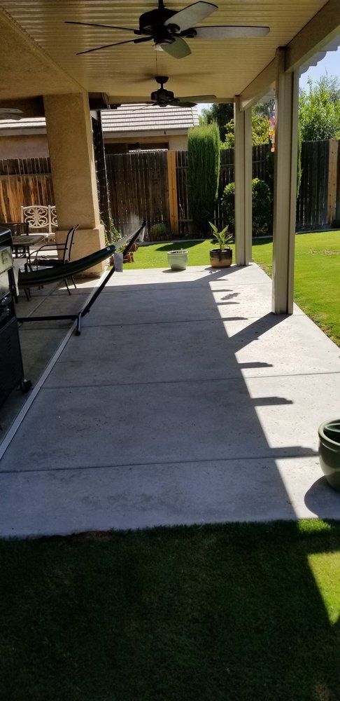 A patio with a ceiling fan and a hammock in the backyard.