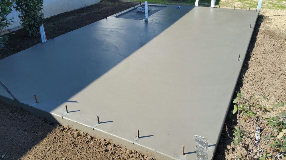 A large concrete slab is sitting on top of a dirt field.
