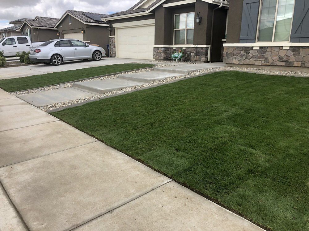 A car is parked in front of a house with a lush green lawn.