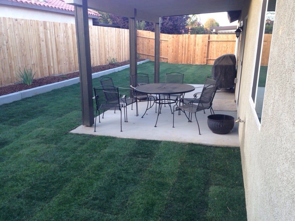 A backyard with a table and chairs under a pergola