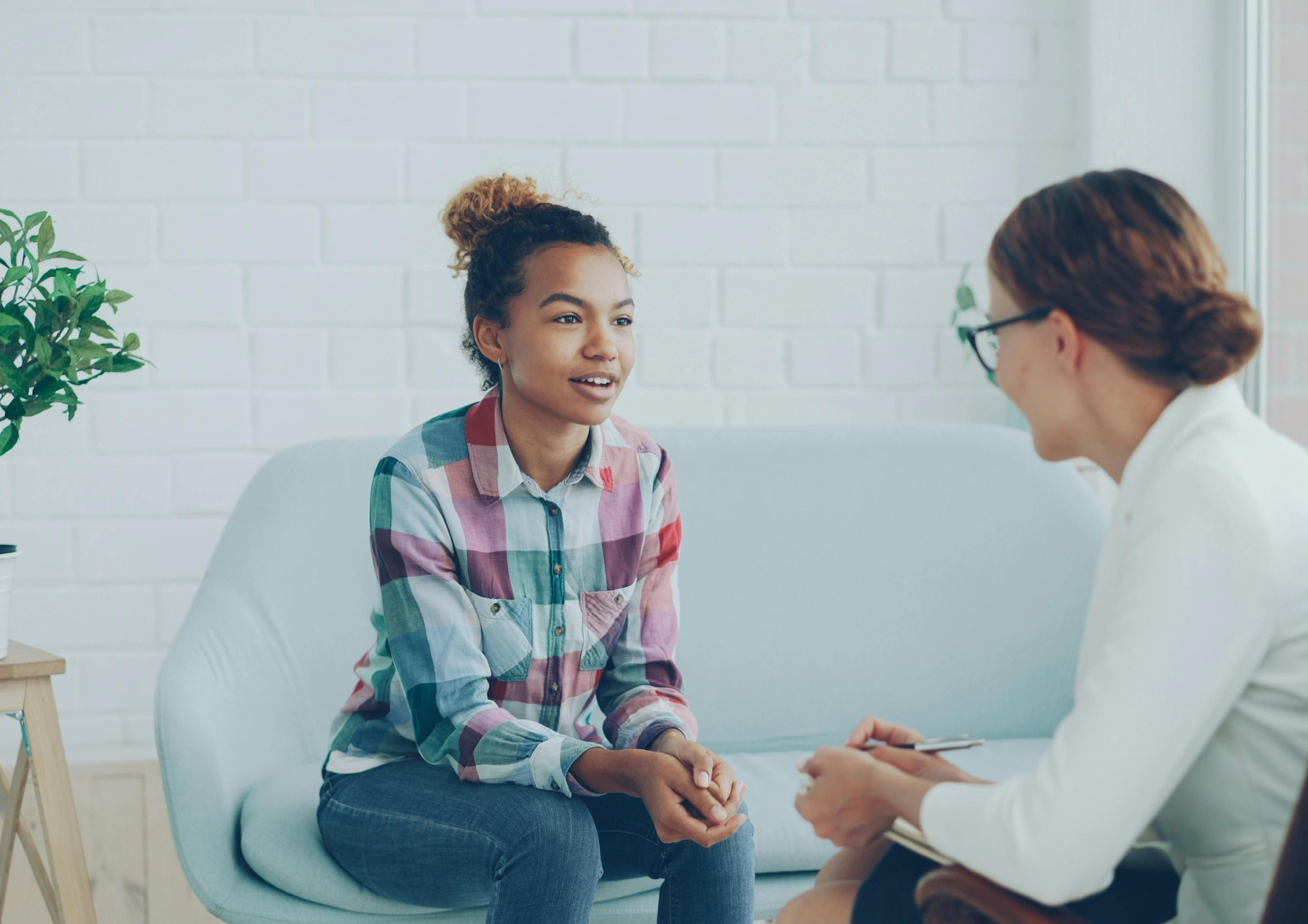 Two people seated in a room, one listening while the other speaks seriously