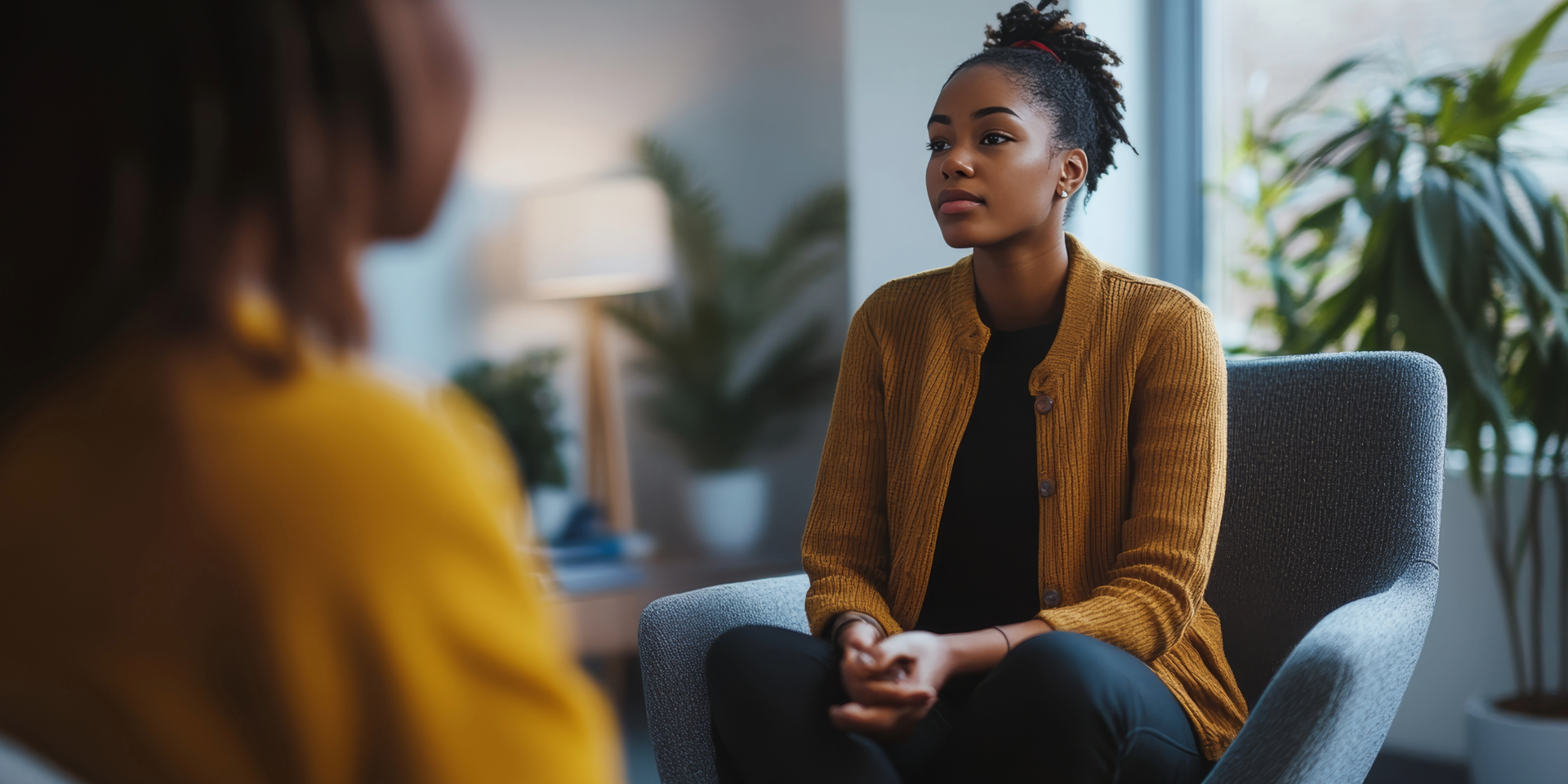 Supportive woman comforting a distressed person on a couch in a bright living room.