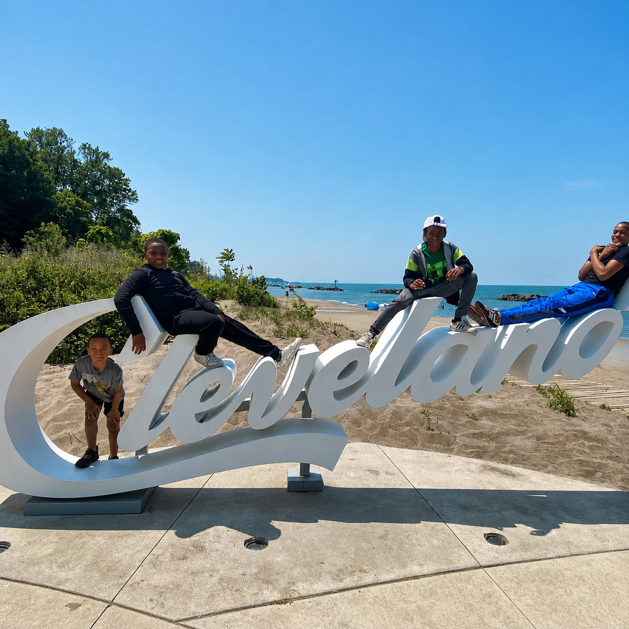 People posing on a large Cleveland sign at a sunny beach with blue sky and lake behind them
