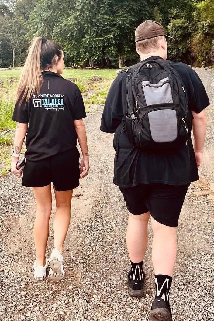 A Man And A Woman Are Walking Down A Dirt Road — Tailored Support Services Pty Ltd In Maroochydore, QLD