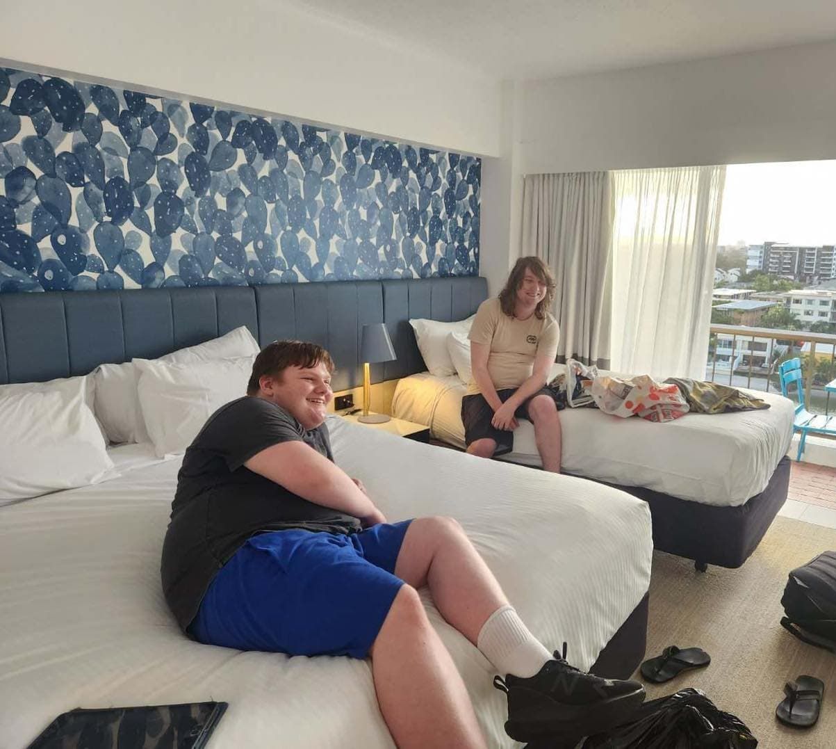 Two People Are Sitting On Beds In A Hotel Room — Tailored Support Services Pty Ltd In Maroochydore, QLD