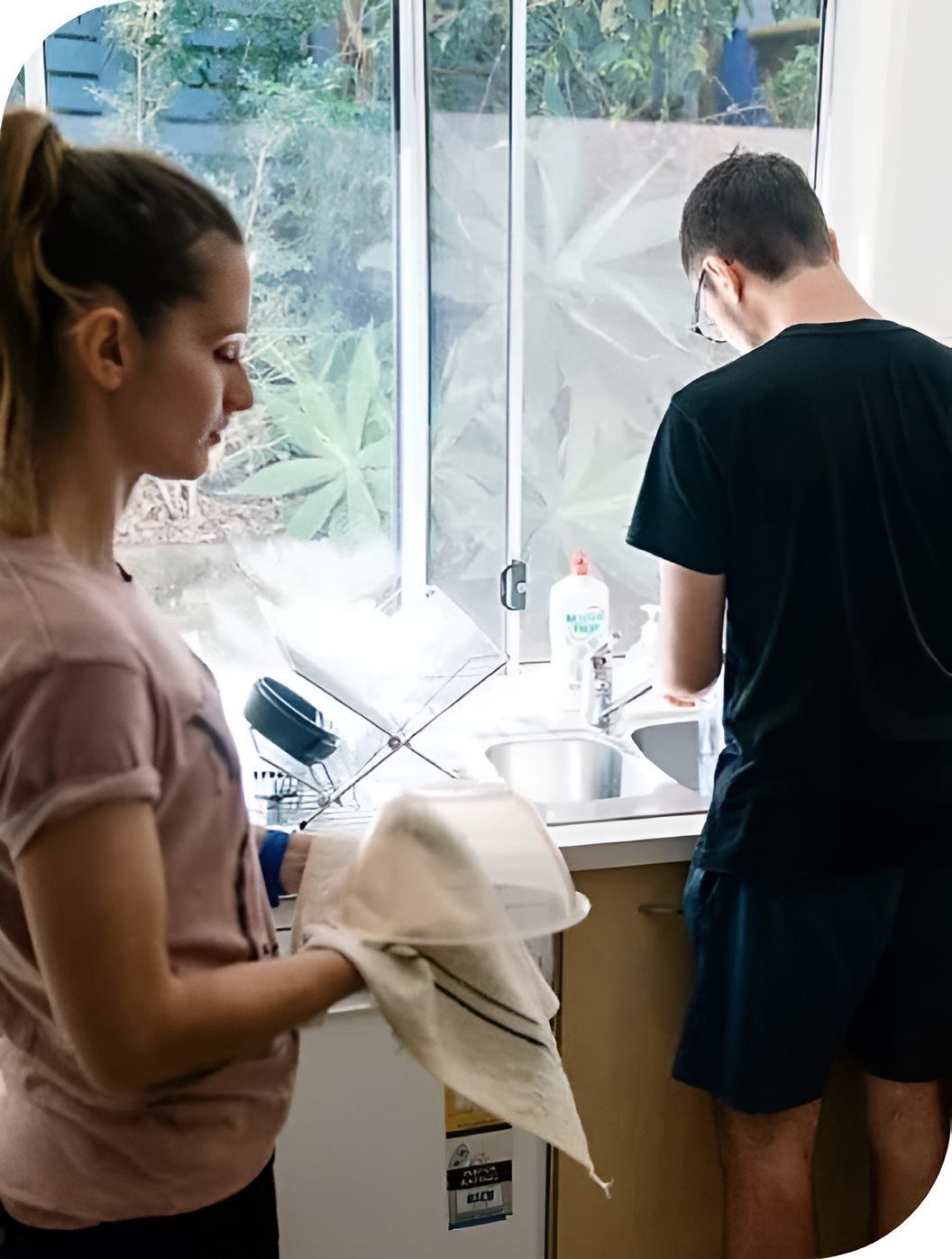 A Man And A Woman Are Washing Dishes In A Kitchen — Tailored Support Services Pty Ltd In Maroochydore, QLD