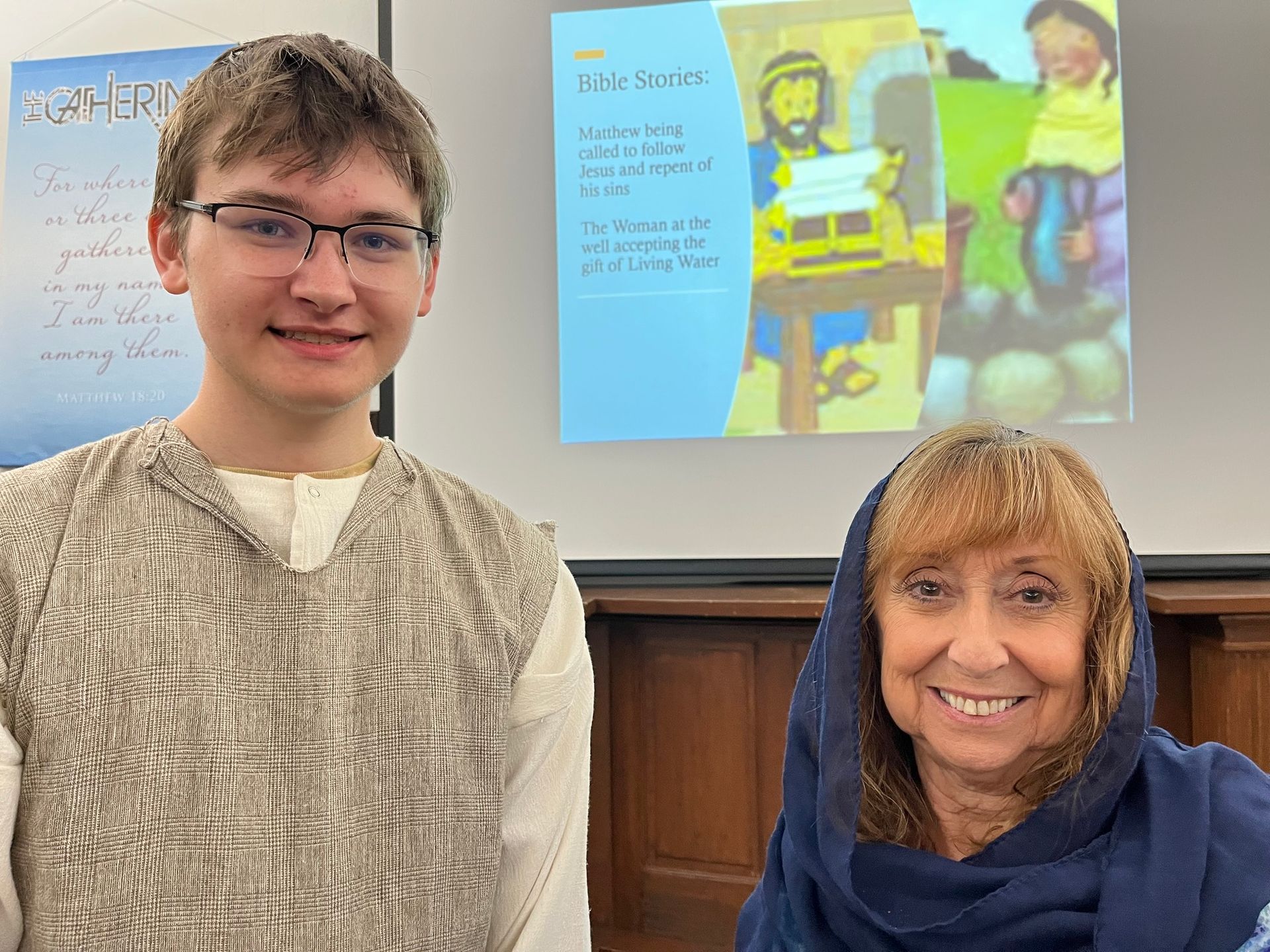 A boy and a woman are posing for a picture in front of a screen that says may