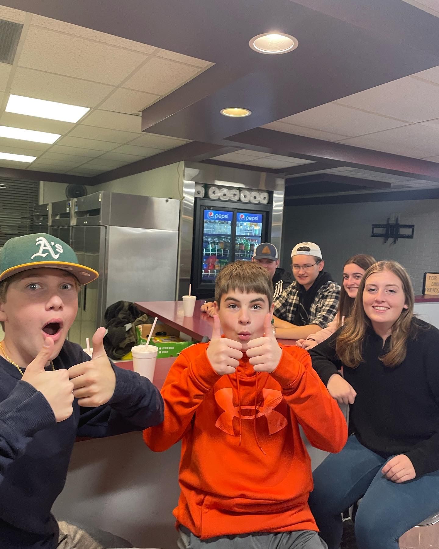 A group of young people giving a thumbs up in a restaurant