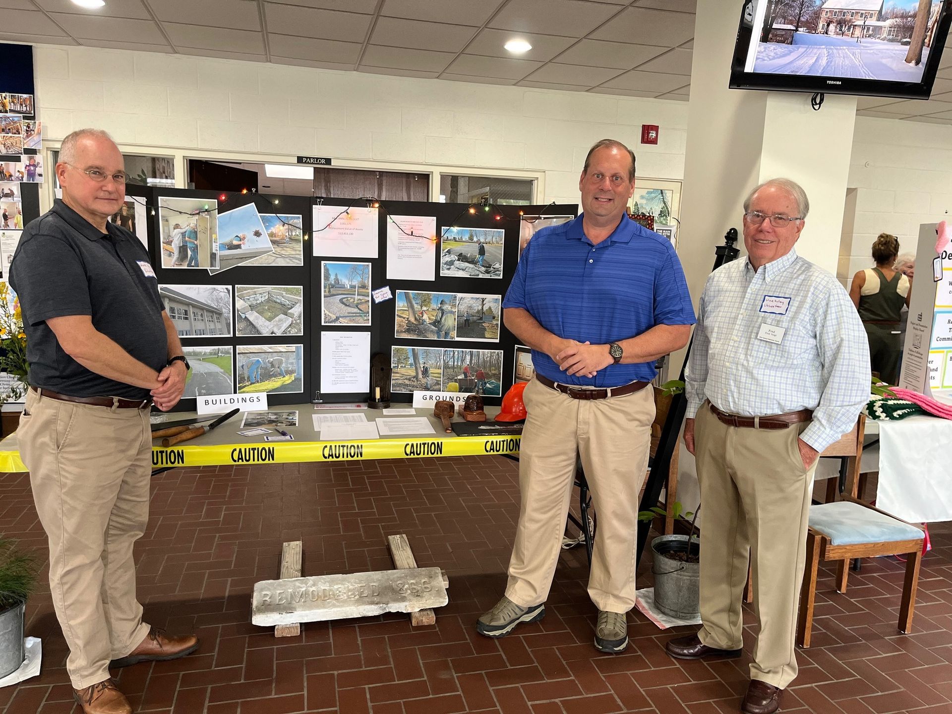 Three men standing in front of a table with pictures on it