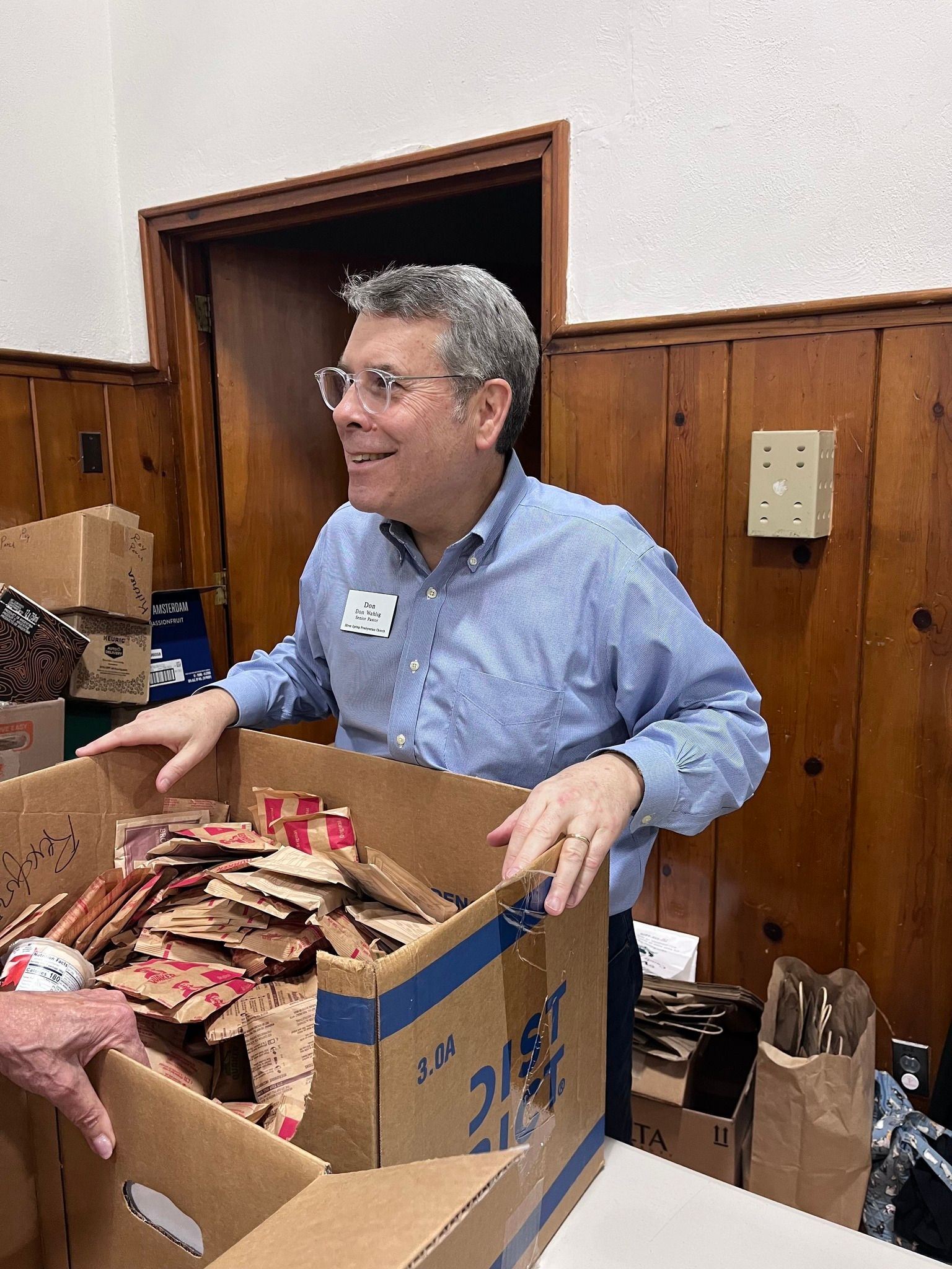 A man in a blue shirt is reaching into a cardboard box with the number 215 on it