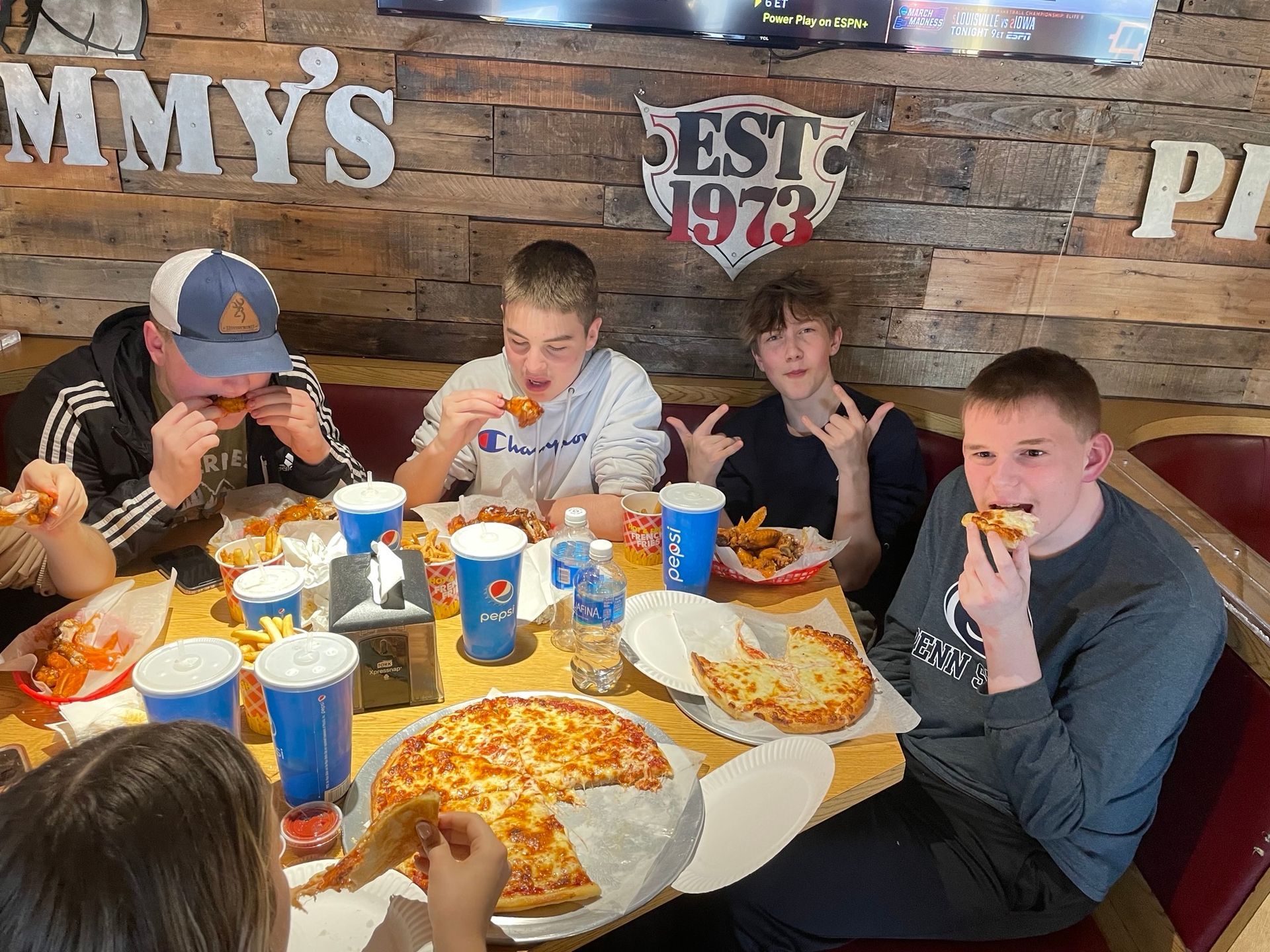A group of young people are eating pizza at jimmy 's pizza