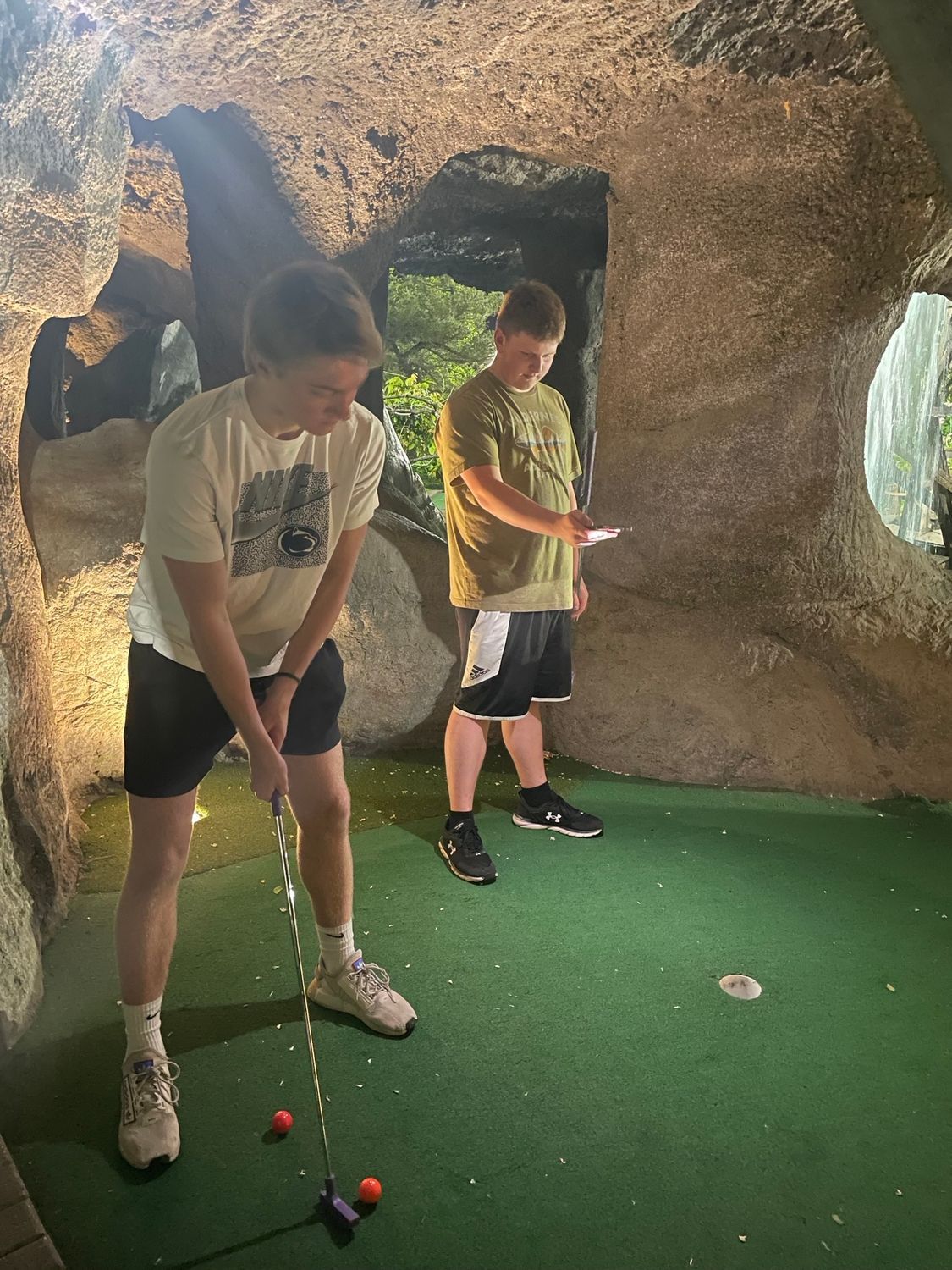 Two boys are playing a game of golf in a cave