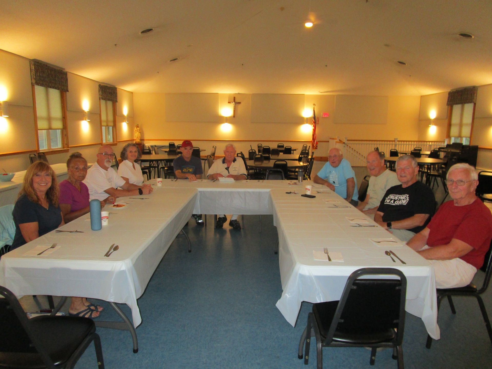Group of people seated around a long, U-shaped table in a brightly lit room.