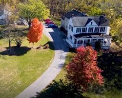 An aerial view of a large white house surrounded by trees and a driveway.