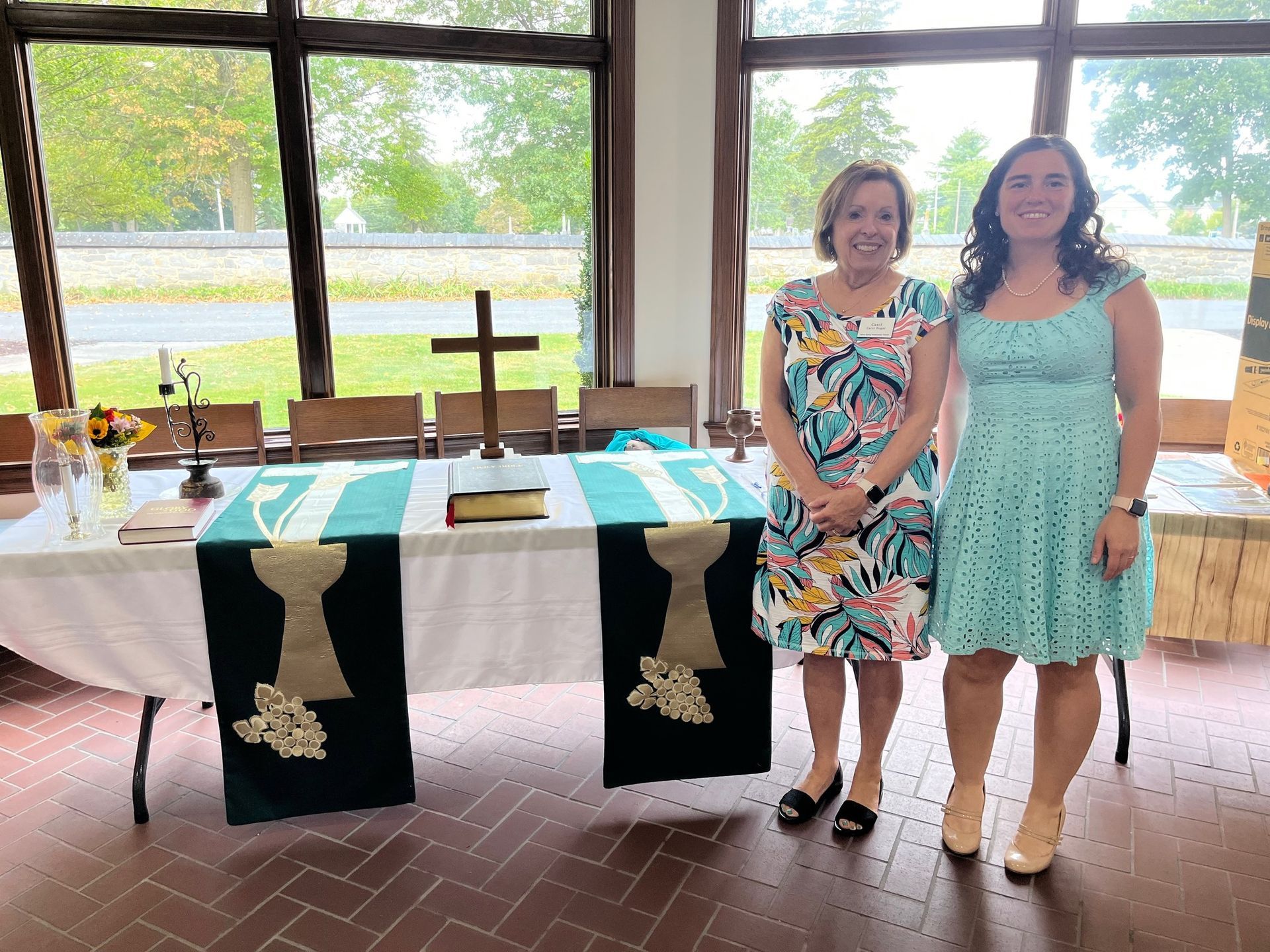 Two women standing in front of a table with a cross on it