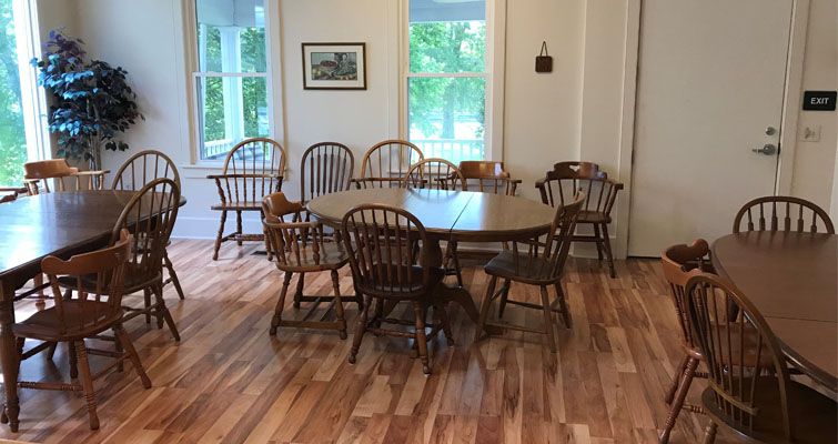 A room with tables and chairs and a picture on the wall