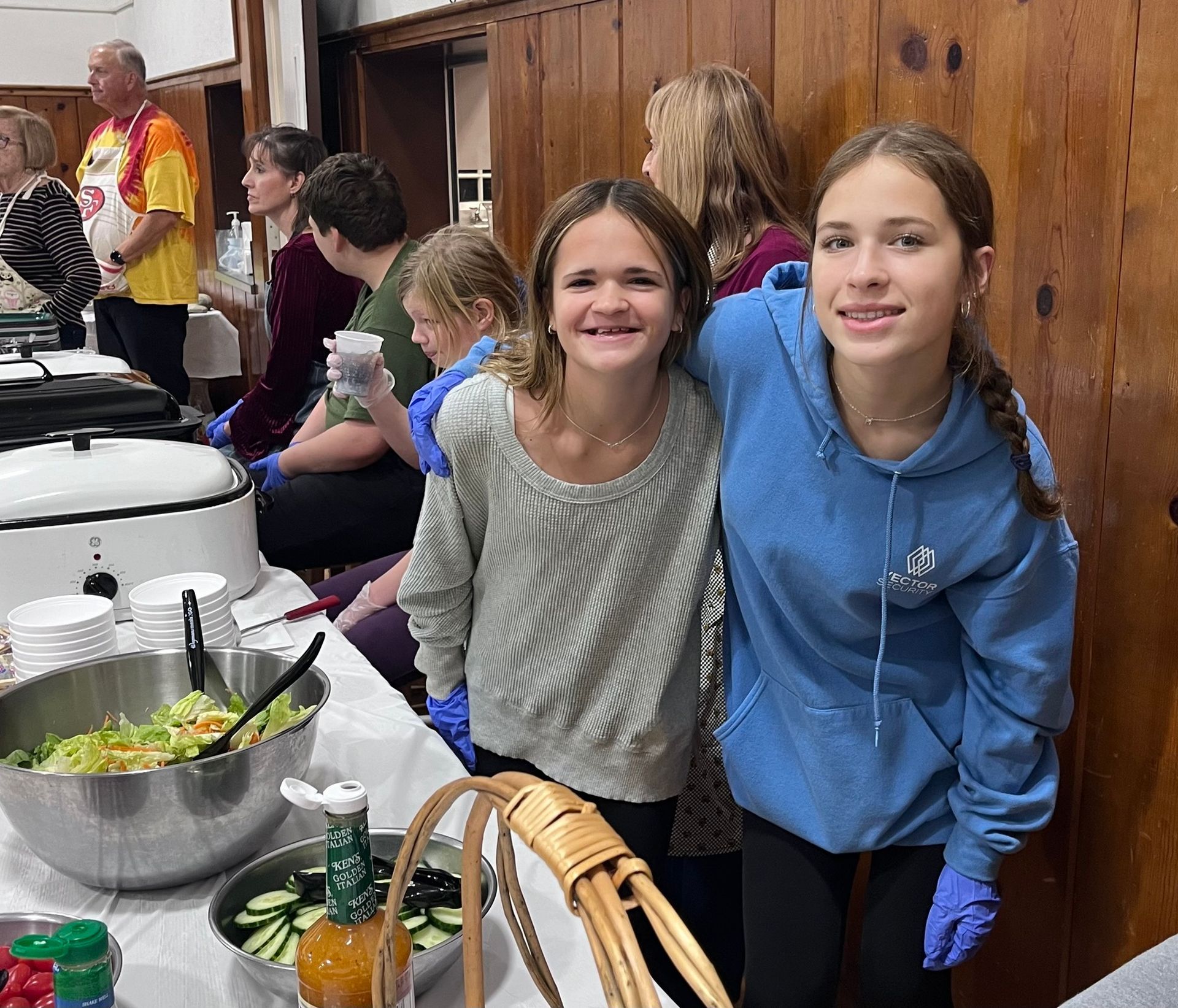 Two girls are posing for a picture in front of a buffet table
