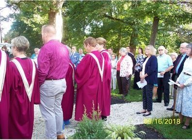 A group of people in purple robes are standing in a park.