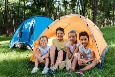 Happy multicultural kids smiling while sitting in yellow camp