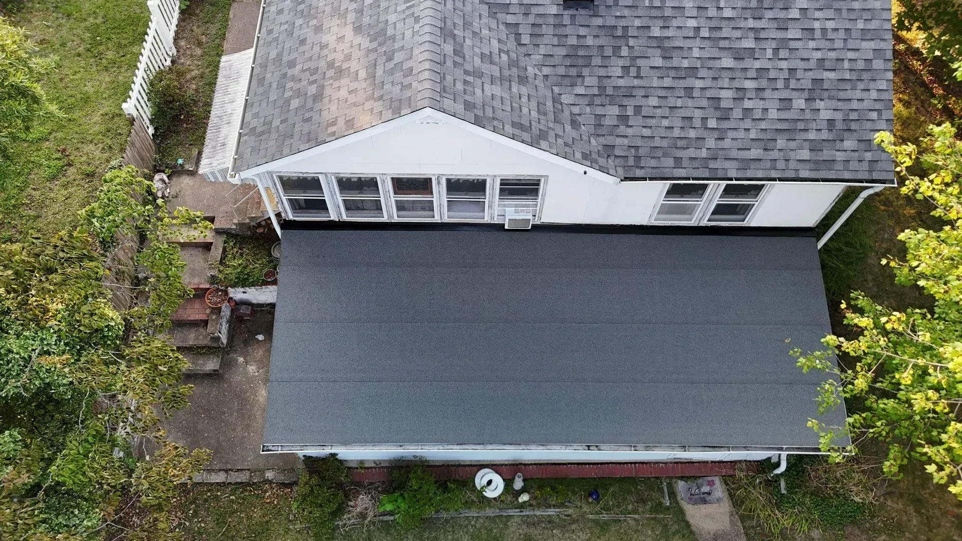 Overhead view of a house with gray shingle roof, white dormers, and a large dark awning over the patio