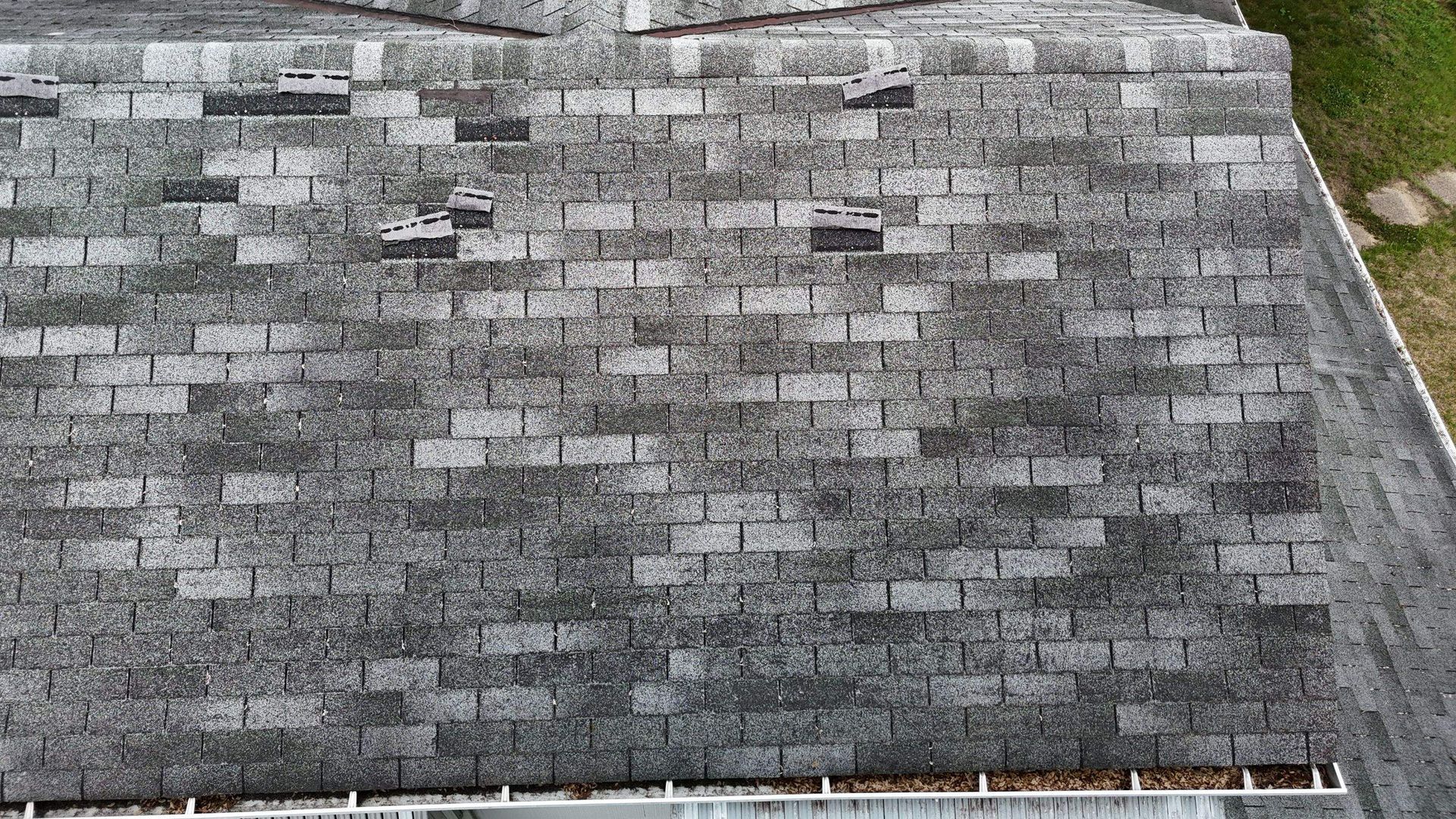 Gray asphalt shingle roof with weathered patches and a small section of gutter visible at the bottom
