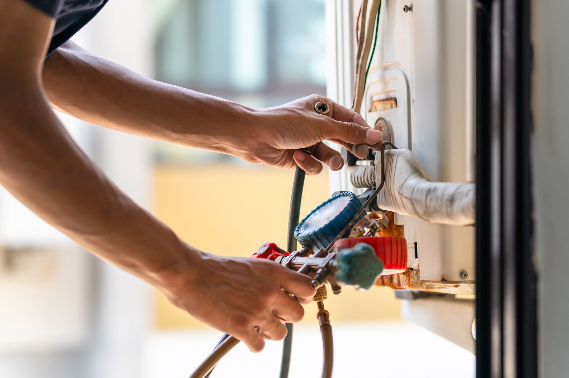 A person connecting gauges to an outdoor air conditioning unit for servicing. A person connecting gauges to an outdoor air conditioning unit for servicing.