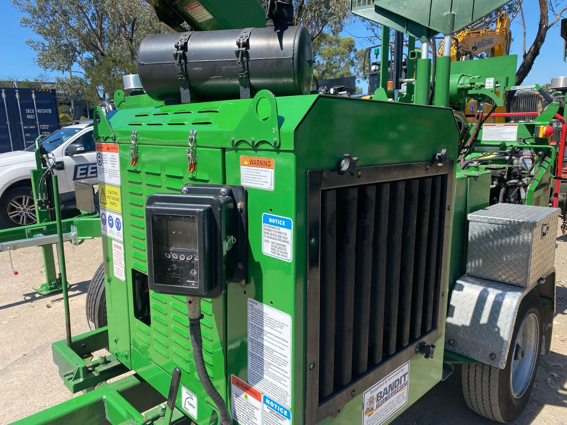 Orange wood chipper truck being filled with chopped wood debris outdoors. — Auz Tree in Hallidays Point, NSW
