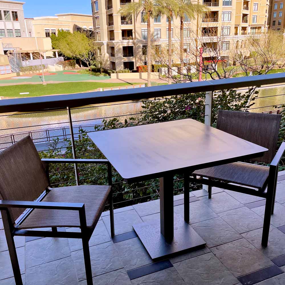 Balcony with two chair and a table facign an office building courtyard