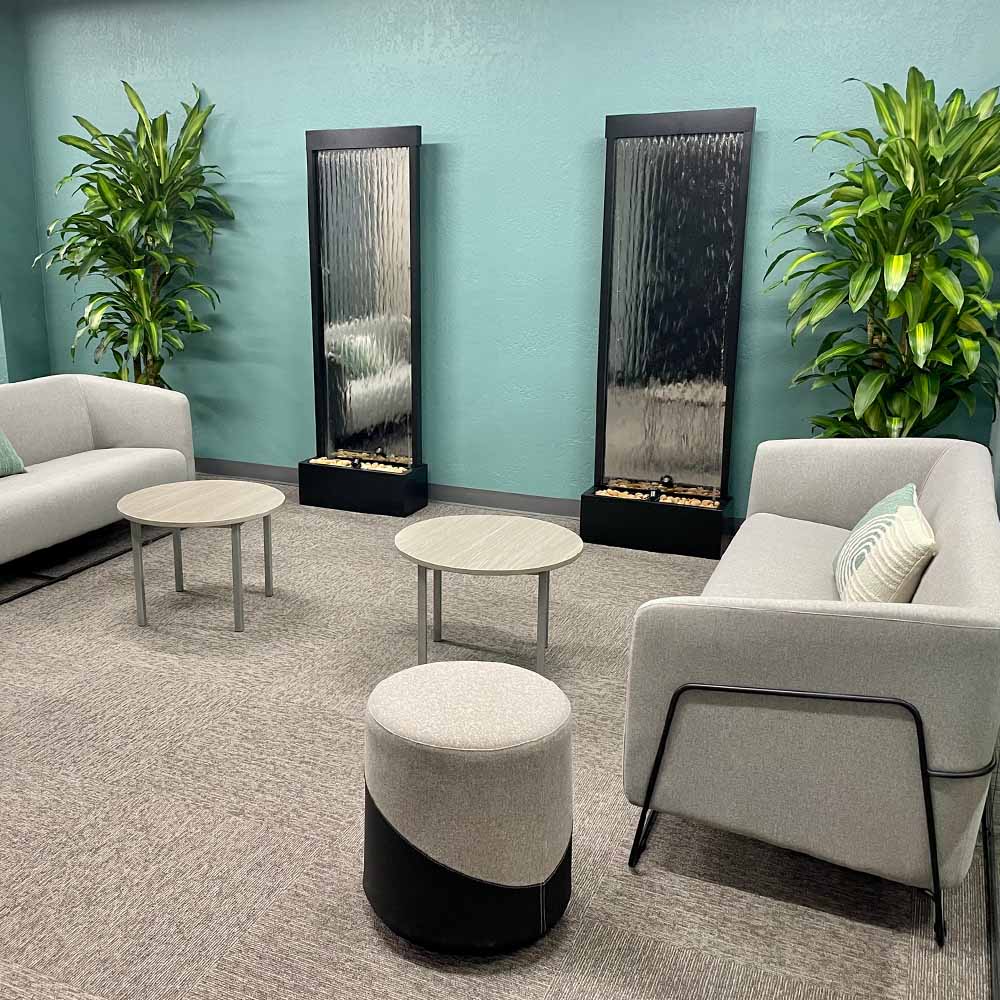 Serene reception area with beige couches, green plans and fountains
