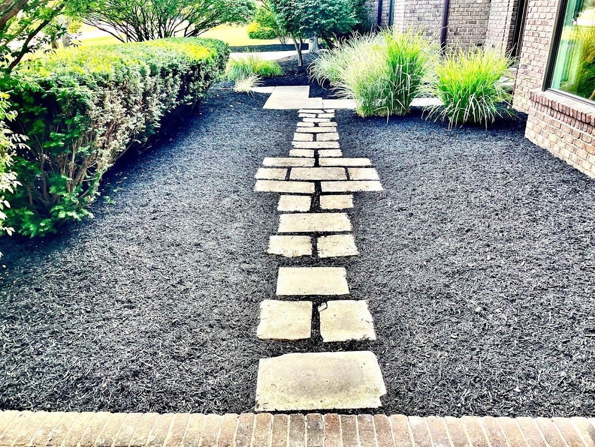 A stone walkway leading to a house in a garden.