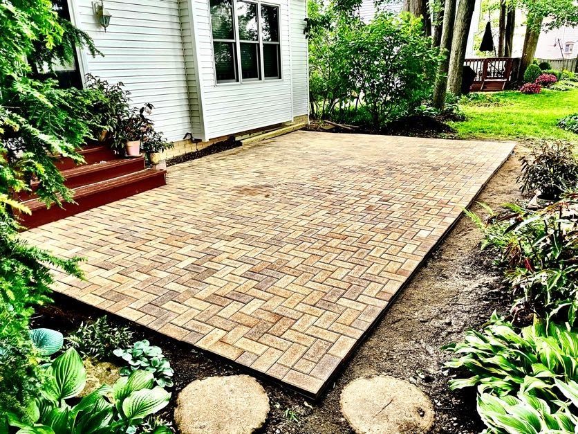 A brick patio is being built in front of a house.
