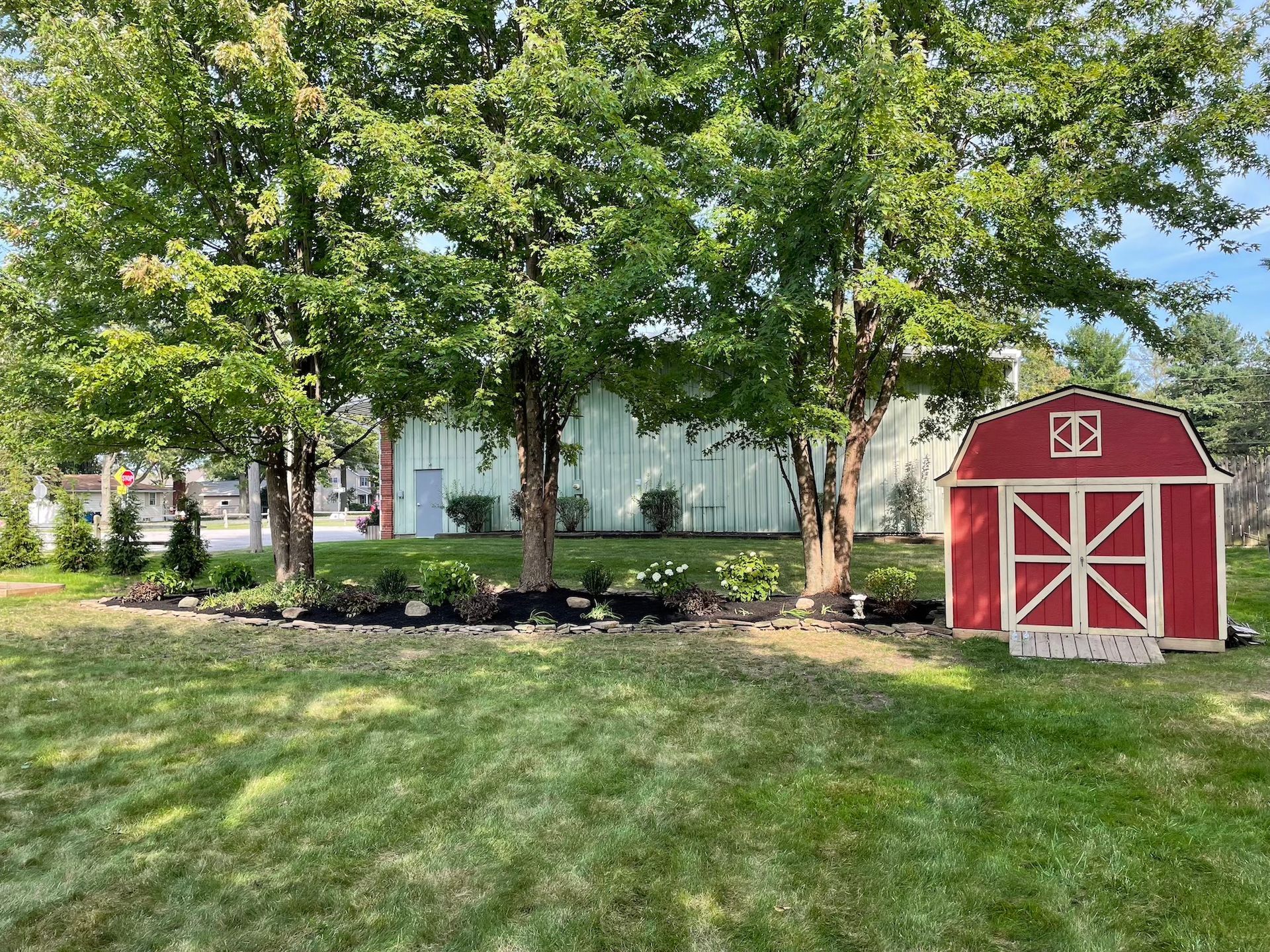 A red barn is sitting in the middle of a lush green field.