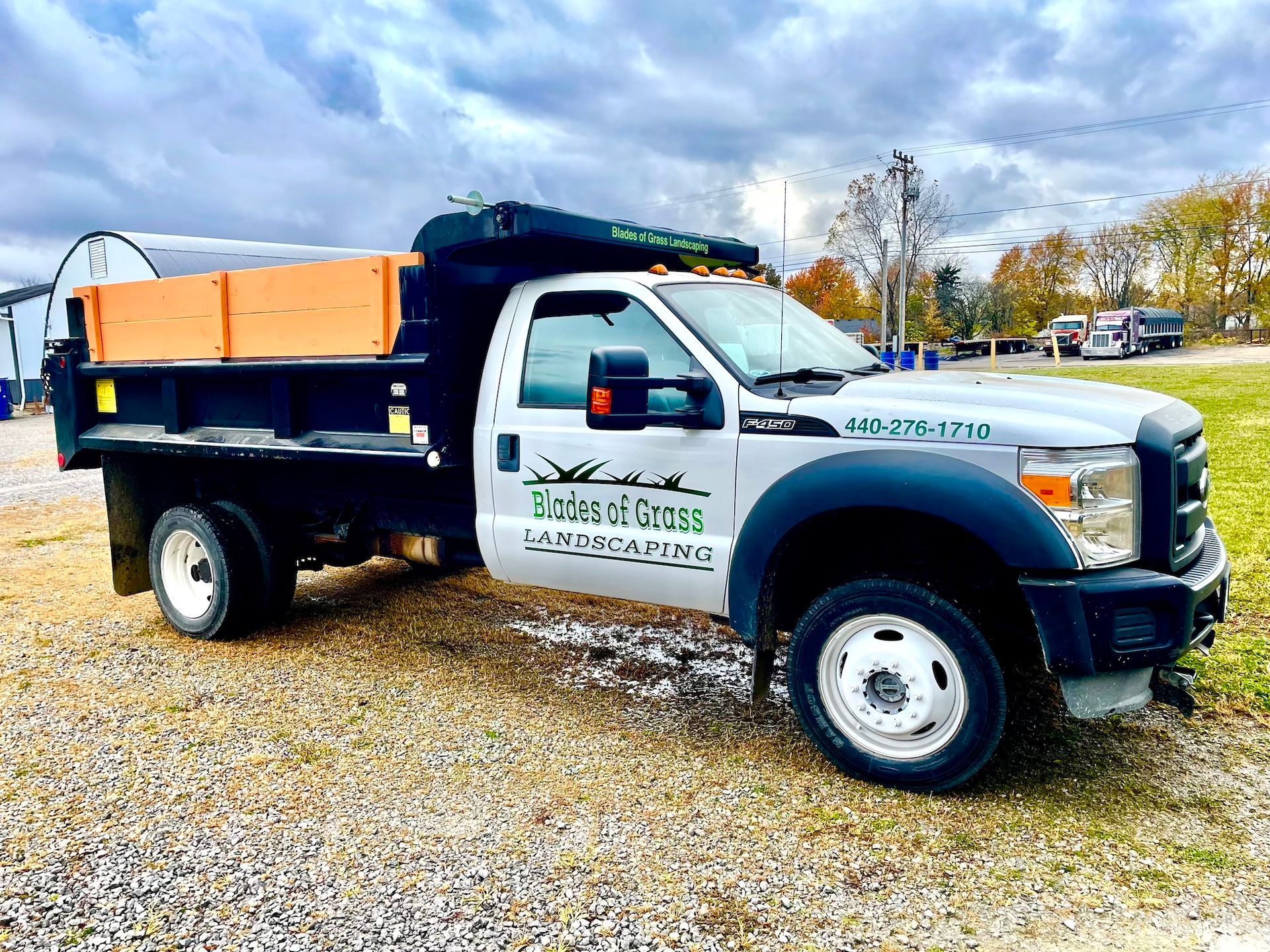 A dump truck is parked in a gravel lot.